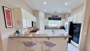 A modern kitchen with white cabinets, granite countertops, a built-in oven, and a window with a view. - 5 Star-Rated Indian Wells 5 Bedroom, Mtn View, Cas (Indian Wells)