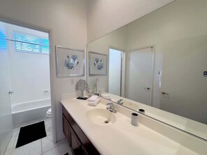 A modern bathroom with a large mirror, a bathtub, and a sink.