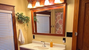 Une salle de bain avec un meuble-lavabo en bois, un évier, un miroir et un porte-serviettes.