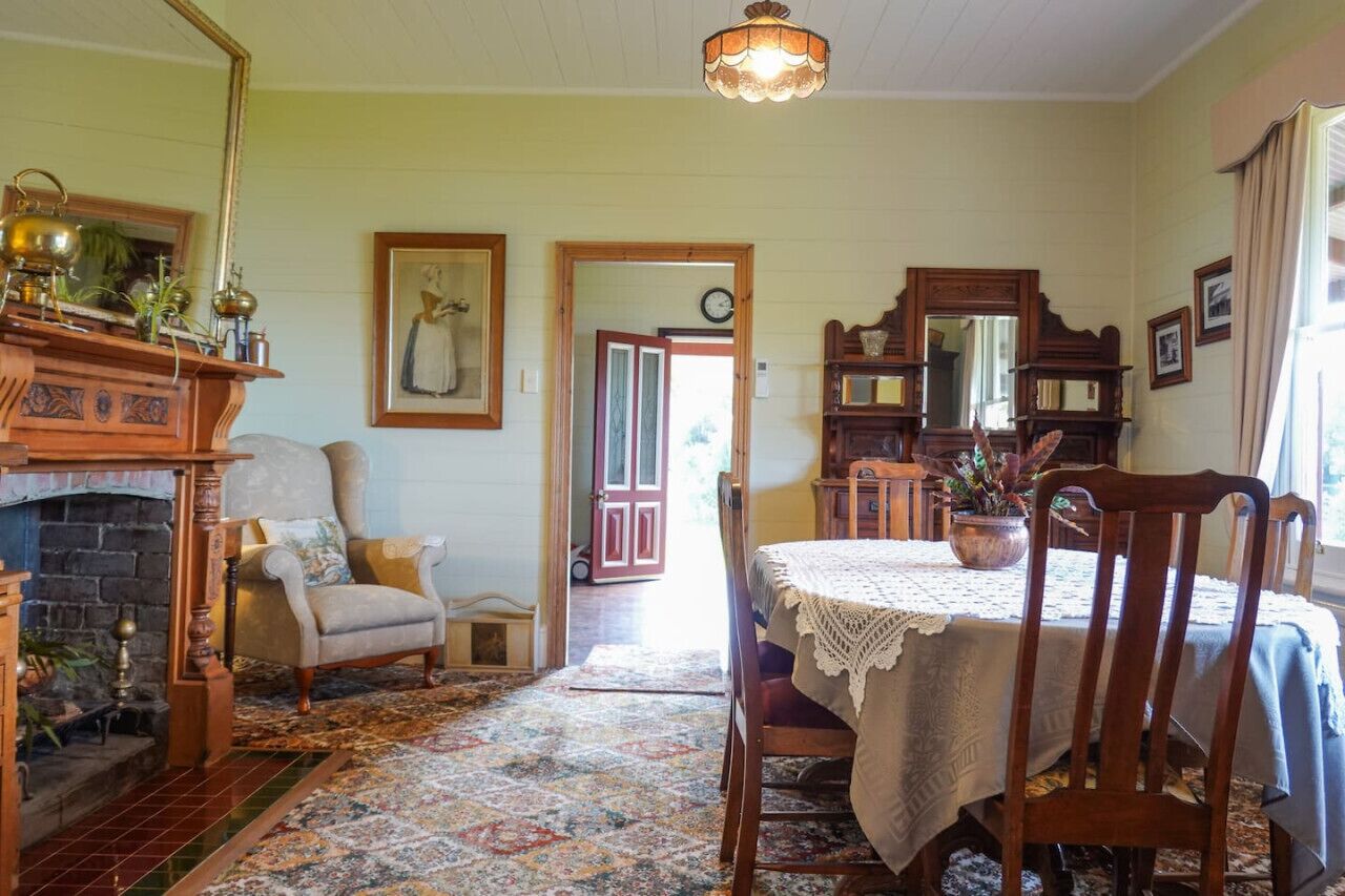 Een klassieke woonkamer met een open haard, een eettafel en een comfortabele fauteuil.