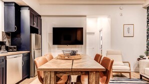 A modern kitchen with dark cabinetry, a built-in oven, and a coffee machine. - Parliament Views | Historic Stone Apartment in Old Quebec (Québec)