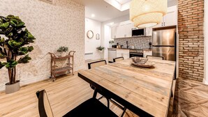 A modern kitchen with white cabinets, a stainless steel refrigerator, and a hanging light fixture. - Bohemian Old Quebec Retreat | Exposed Brick & Character (Québec)