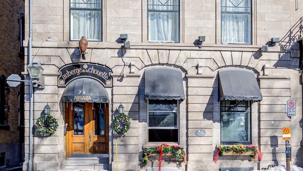 Un edificio histórico con fachada tradicional, múltiples ventanas y acceso principal a nivel de calle con un letrero.