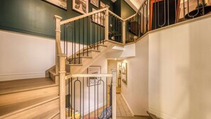 Una escalera de madera con barandilla de metal que sube a un segundo piso.