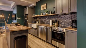 Una cocina moderna con electrodomésticos de acero inoxidable, encimeras de madera y salpicadero de azulejos tipo espiga.