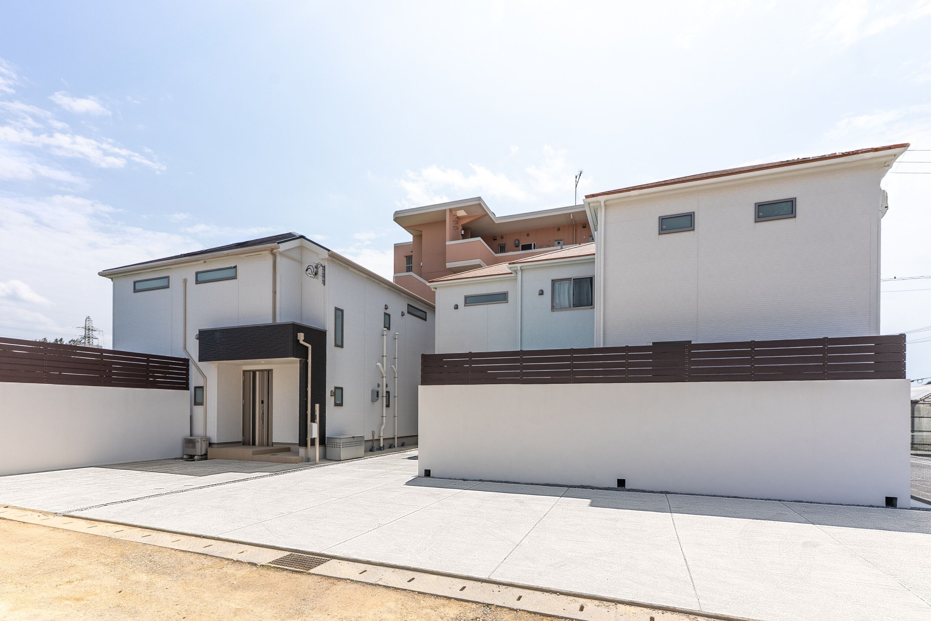A modern residential building with a flat roof, a central entrance, and a covered outdoor area.