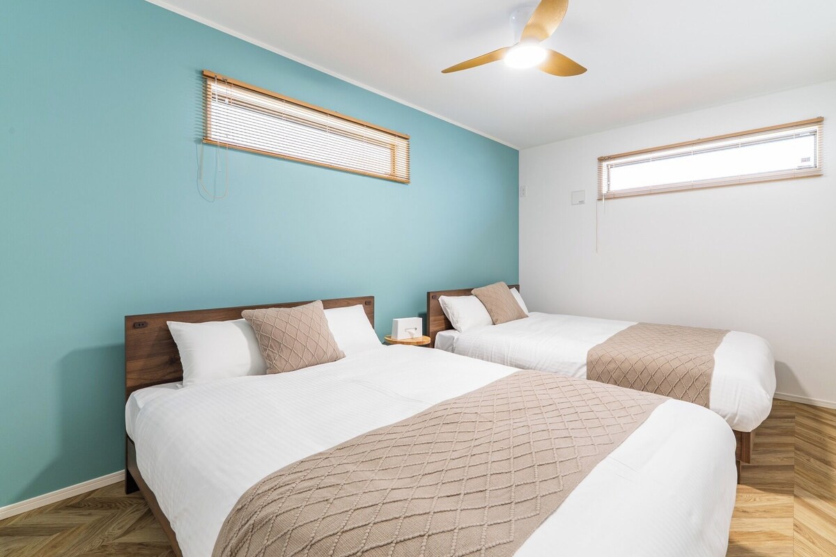 A room with two beds, wooden headboards, and a ceiling fan.