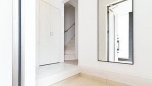 A hallway with a white wardrobe, a mirror, and a staircase leading to another room. - Grandioso Okinawa Pool Villa Onna 8 (Onna)