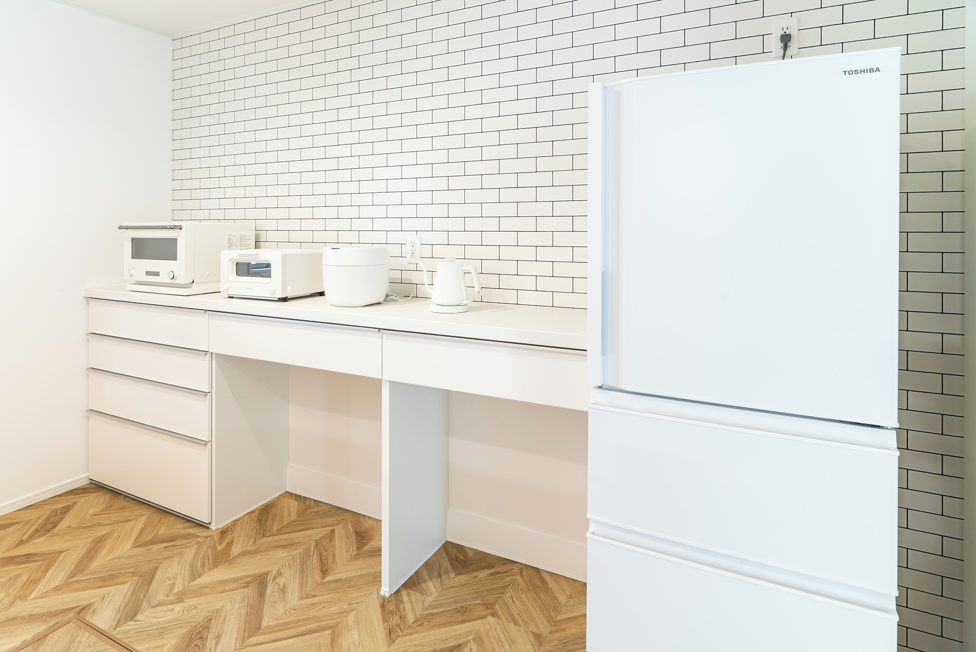 A kitchen with a white refrigerator, a microwave, a coffee maker, and a toaster on the counter.