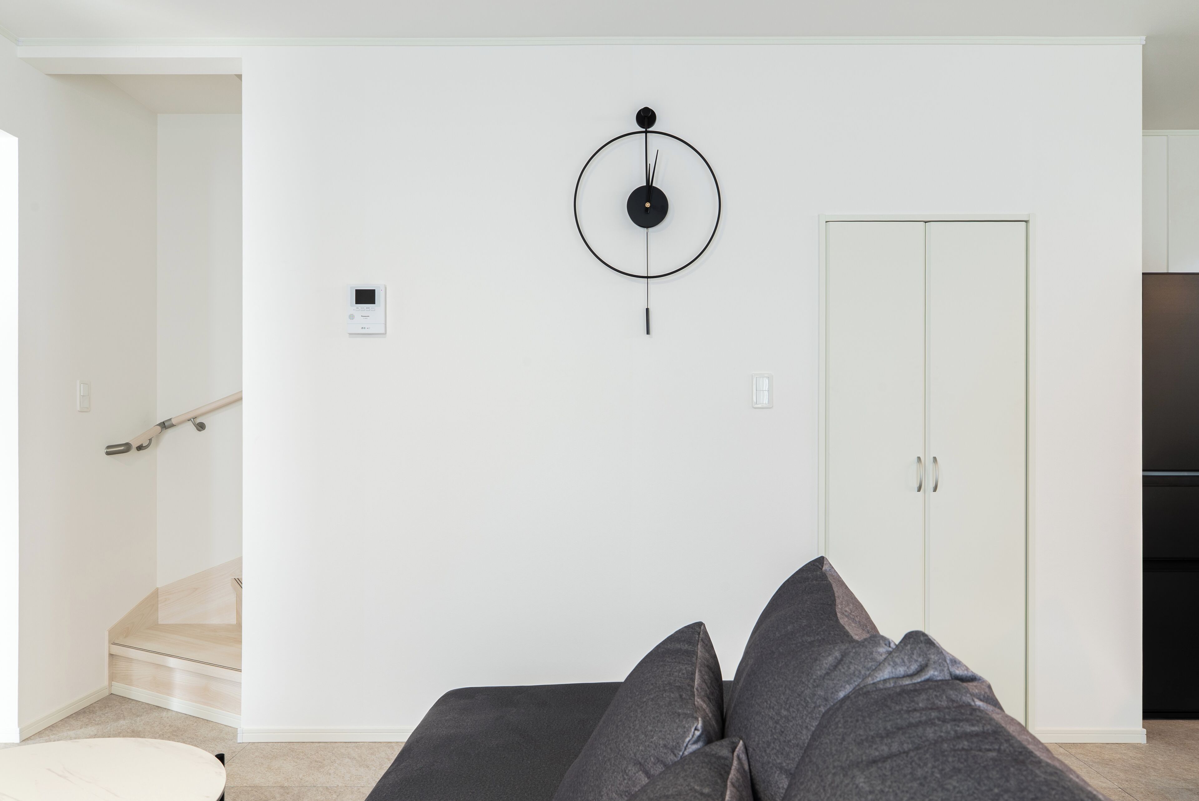 A modern living room with a sofa, a wall-mounted light fixture, and a wardrobe.