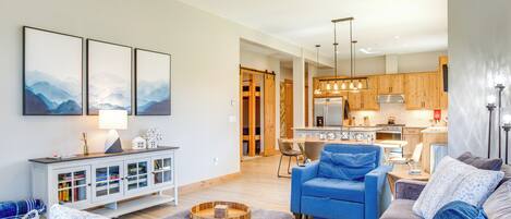 A modern living room with a blue sofa, grey ottoman, and a white cabinet with glass doors.