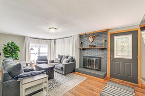 A modern living room with a grey sofa set, a fireplace, and a large window with curtains. - Walk to Water: Lake House in Suring! (Suring)