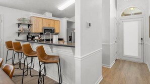 Una cocina moderna con barra, armarios de madera y un refrigerador de acero inoxidable.