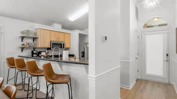 Una cucina moderna con angolo bar, mobili in legno e frigorifero in acciaio inossidabile.