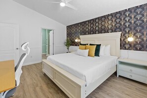 Une chambre à coucher comprenant un lit, une table de chevet, une commode et un ventilateur de plafond.