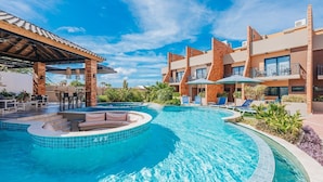 A hotel with a swimming pool, outdoor seating, and a covered area.