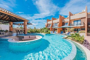 A hotel with a swimming pool, outdoor seating, and a covered area. - 3BR House Pool Gym 7-Min Walk to Palm Beach - Porta al Sole 15 by Bocobay (Noord)