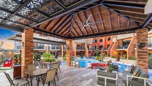 An outdoor pool area with a wooden ceiling, lounge chairs, and a dining table. - New LUXE Townhouse 5 min walk Ritz/Palm Beach #15 (Noord)