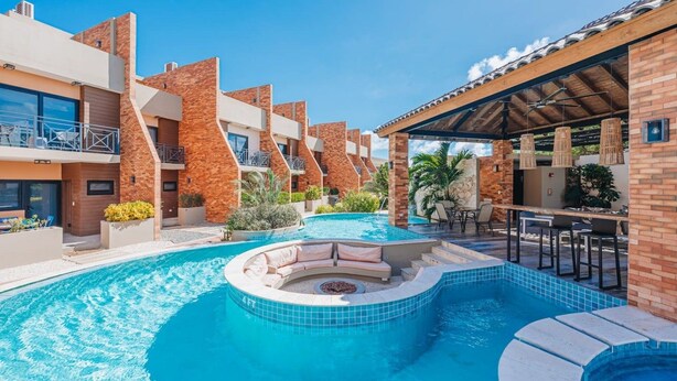A swimming pool with a hot tub and lounge area, surrounded by multi-story buildings with balconies.