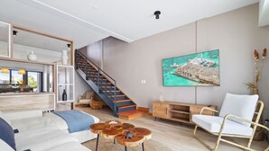 A modern living room with a staircase, a large painting, and a white chair. - New LUXE Townhouse 5 min walk Ritz/Palm Beach #15 (Noord)