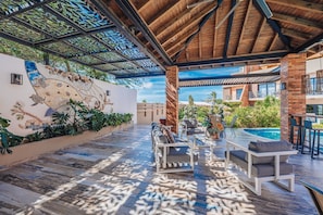 A covered outdoor area with a pool, seating, and a decorative wall.