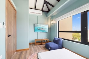 Een slaapkamer met een bed, een raam met uitzicht, een schilderij aan de muur en een houten bankje.