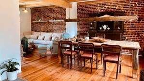 A rustic kitchen with exposed brick walls, wooden beams, and a dining area with a wooden table and chairs. - Holiday Home 'Am Rande Des Spreewald' with Private Terrace, Private Garden and Wi-Fi (Heinersbrück)