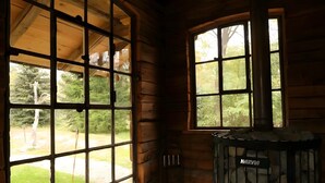 A log cabin interior with a large window, a Harvia wood stove, and patterned floor tiles. - Holiday Home 'Am Rande Des Spreewald' with Private Terrace, Private Garden and Wi-Fi (Heinersbrück)