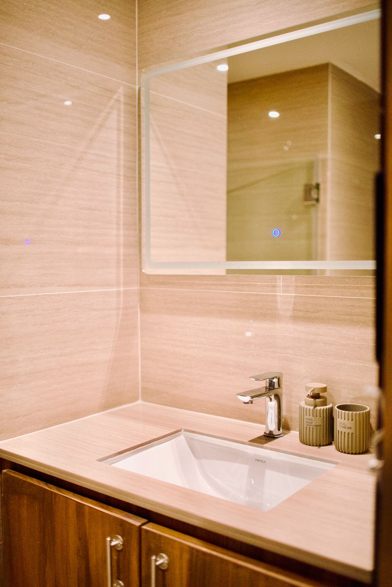 A bathroom with a wooden vanity, a white sink, and a mirror.