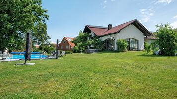 Ein Haus mit Swimmingpool, Rasen und Garten.
