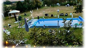 Une piscine avec des chaises longues, une tente et un kiosque, le tout installé dans un espace verdoyant.