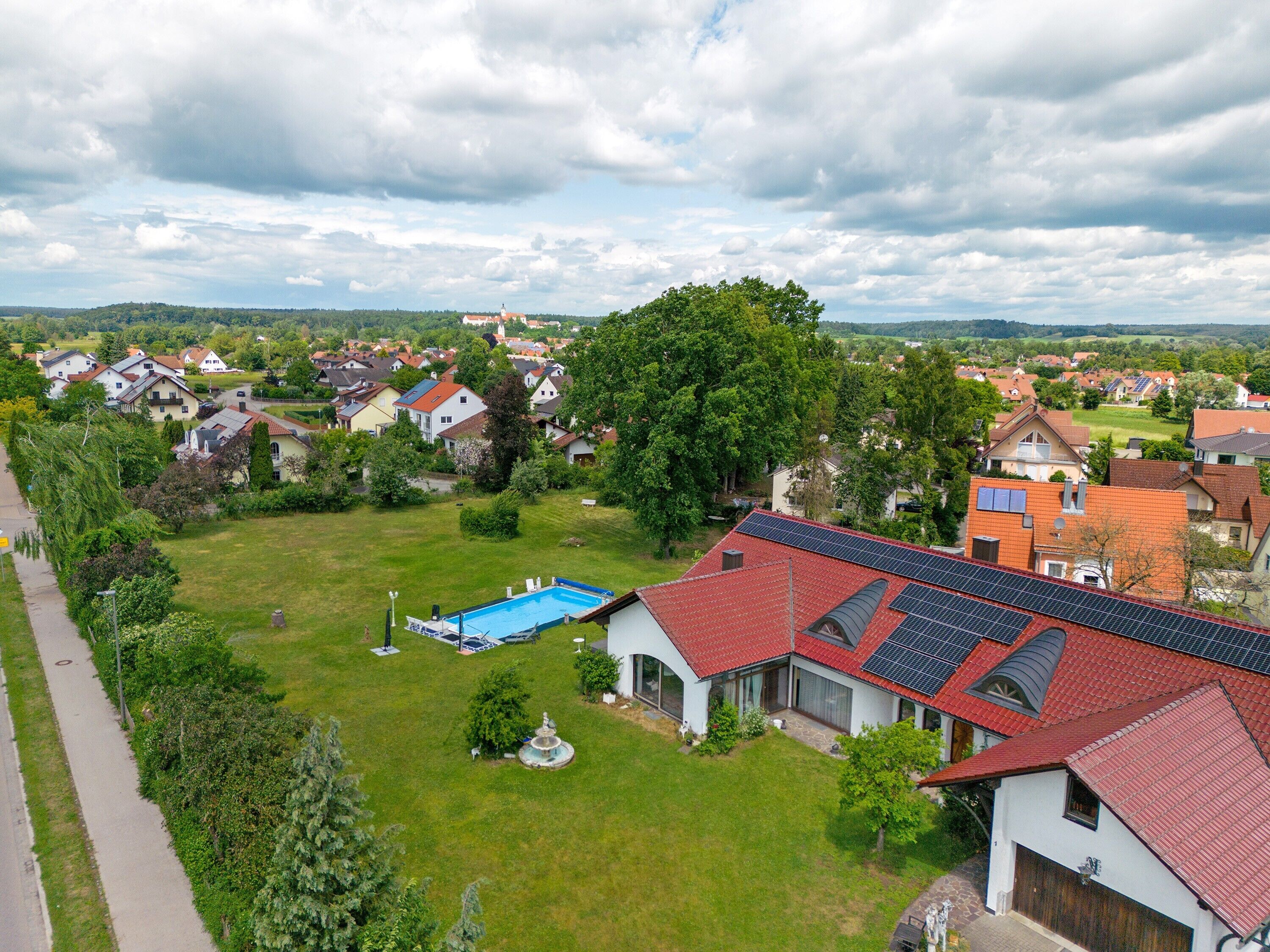 Een woonwijk met huizen, een zwembad en zonnepanelen.