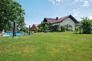 Ett hus med en swimmingpool, en gräsmatta och en trädgård.