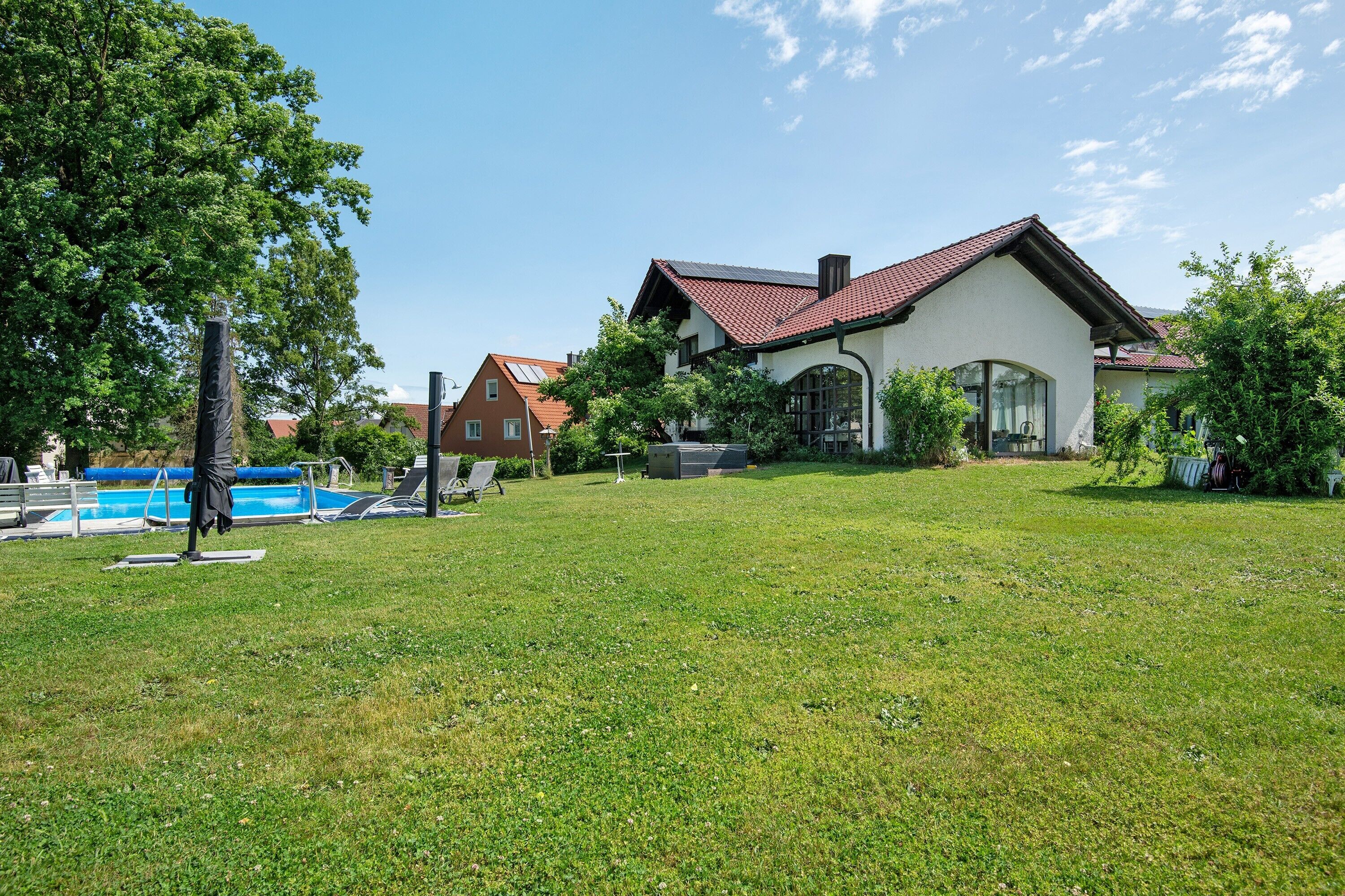 Una casa con piscina, césped y jardín.