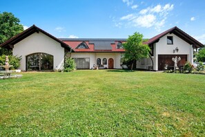 Ein zweistöckiges Haus mit rotem Ziegeldach, einem großen Vorgarten und einer Garage.
