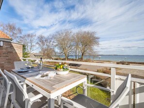 A wooden deck with a table and chairs, overlooking a body of water and trees. - Apartment 'Wellness-Appartement Waterkant' with Sea View, Shared Garden and Wi-Fi (Glücksburg (Ostsee))