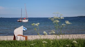 A beach with a sailboat, a chair, and a grassy area.