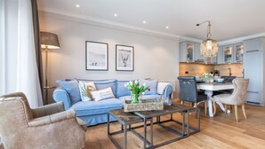 A modern living room with a sofa, armchair, coffee table, and a dining area with a table and chairs.