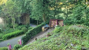 A garden pathway with a wooden structure, a house, and dense greenery.
