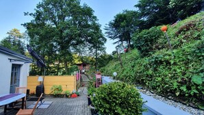 A patio area with a table and chairs, a yellow fence, and a small garden.