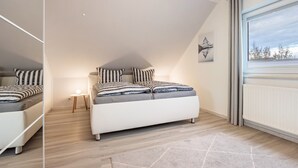 A bedroom with a bed, bedside table, lamp, and a window with curtains. - Apartment 'Celle-Bostel' with Private Terrace, Garden, and Wi-Fi (Celle)