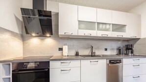 A modern kitchen with white cabinetry, a built-in oven, and a dishwasher. - Apartment 'Celle-Bostel' with Private Terrace, Garden, and Wi-Fi (Celle)
