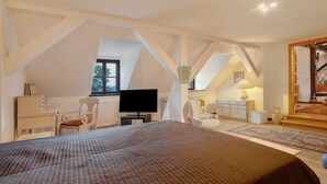 A bedroom with a bed, a TV, a chair, a dresser, and a window.
