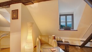 A loft-style bedroom with a sloped ceiling, a bed, a table, and a window.
