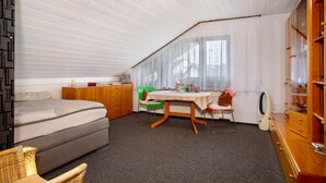 Una habitación con cama, una mesa con sillas, un radiador y un armario.