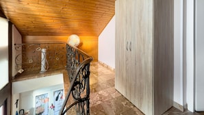 Techo de madera, un ventilador, una escalera y un armario.