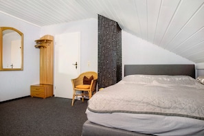 Een slaapkamer met een bed, een kaptafel, een stoel, een spiegel en een behang met een patroon.