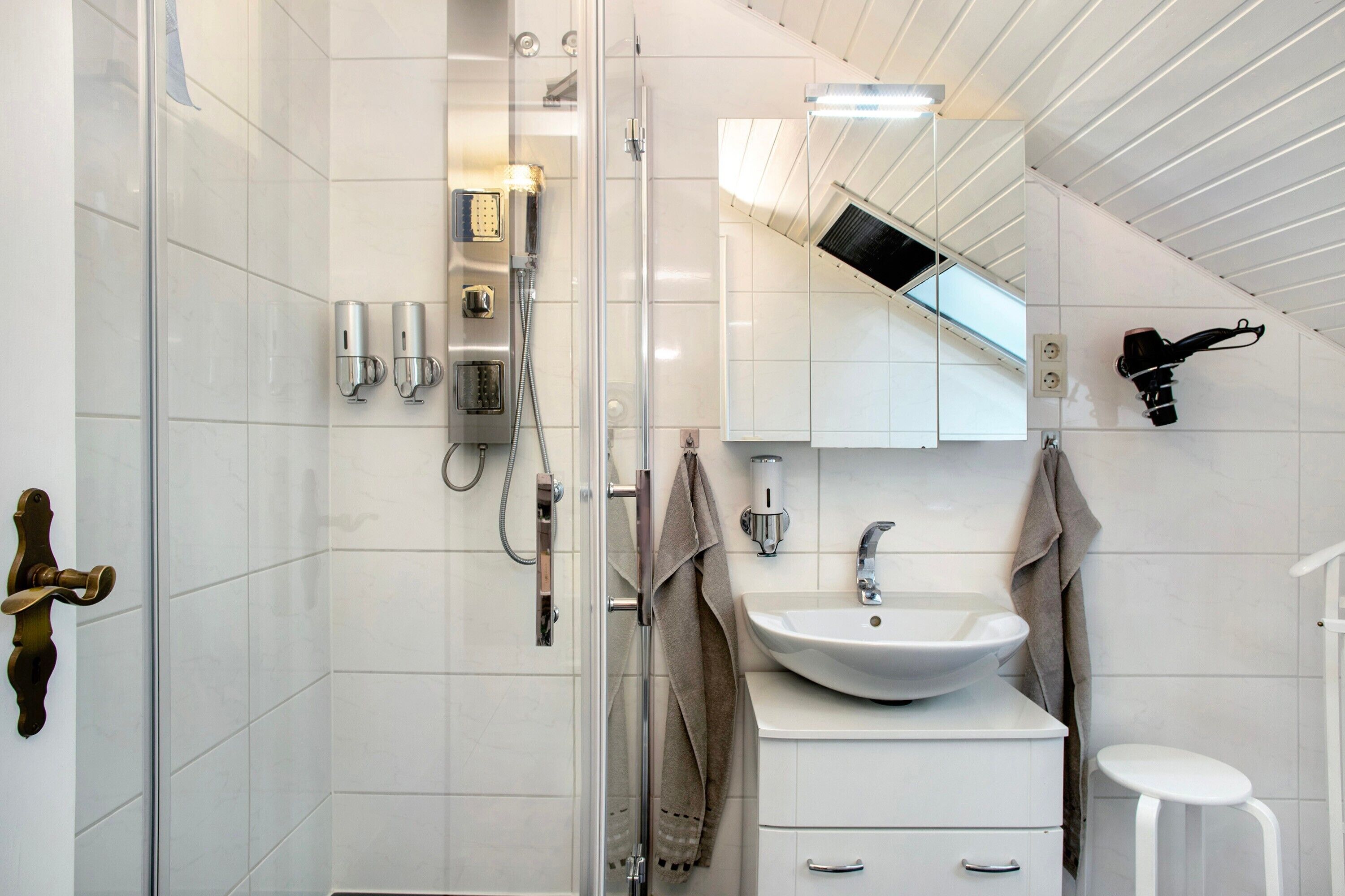 Ein modernes Badezimmer mit einer Duschkabine aus Glas, einem weißen Waschbecken und einem Spiegel darüber.