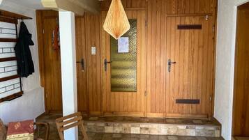 A room with a wooden door, a bench, a table, and a hanging light fixture.
