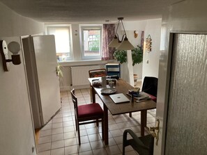 Uma área de refeições com uma mesa de madeira, cadeiras, um laptop e um radiador.